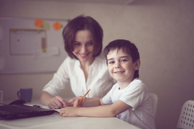 Happy mother is engaged in a laptop with her son preschooler, a real european interior, 