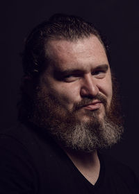 Close-up of bearded man against black background