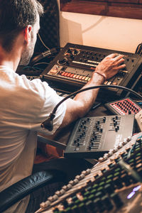 Man operating sound mixer while sitting at table