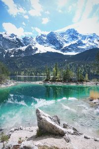 Scenic view of lake by snowcapped mountains against sky