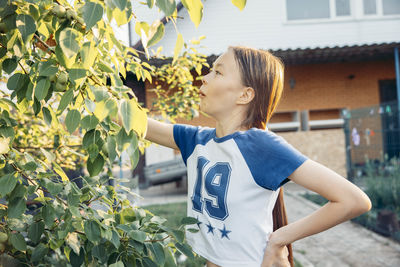 Young woman standing against plants