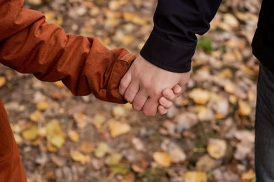 Dad firmly holds the hand of a child in the autumn forest