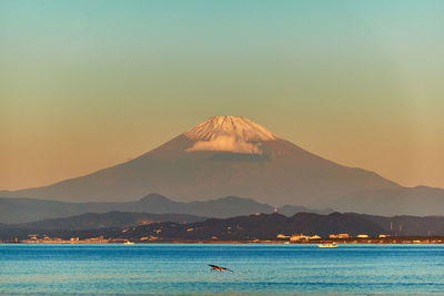 Scenic view of sea and snowcapped mountain against sky during sunrise