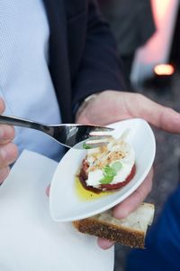 Midsection of man holding caprese salad and fork