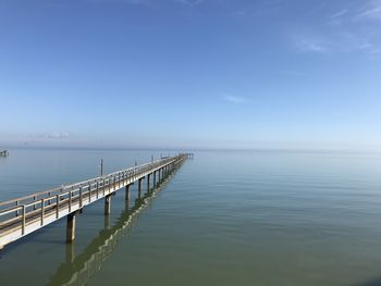 Pier over sea against blue sky