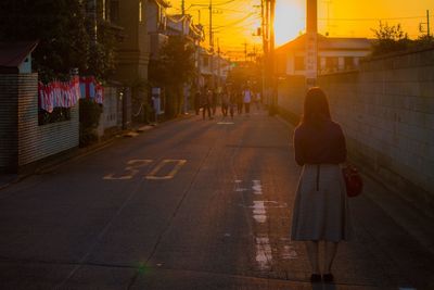 Woman walking on road at sunset