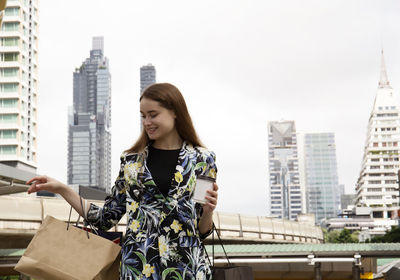 Young woman standing against buildings in city