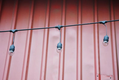 Low angle view of light bulb hanging on wall