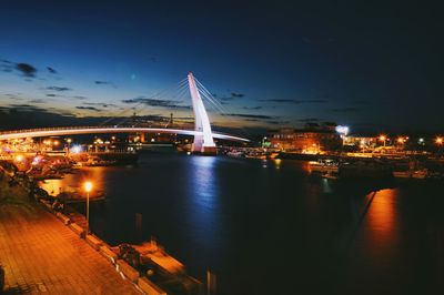 Illuminated suspension bridge over river at night