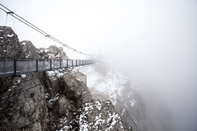 Narrow footbridge against rocky mountains
