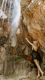 Rear view of woman standing by waterfall