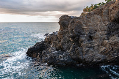 Rock formation in sea against sky