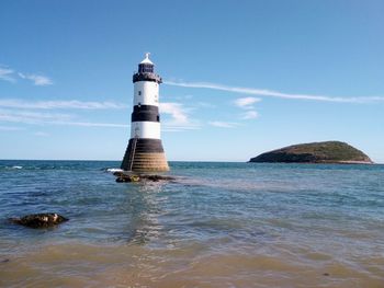 Lighthouse by sea against sky