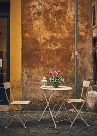 Empty chairs and table against building