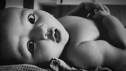 Close-up portrait of baby girl lying on bed