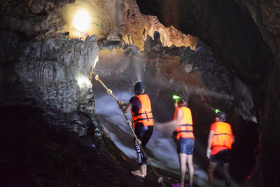 People standing by stream in cave