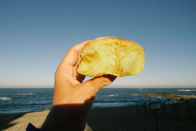 Close-up of hand holding ice cream against sea