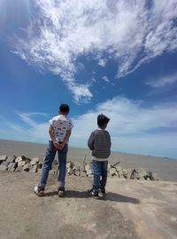 Low angle view of man standing on sea looking at sky
