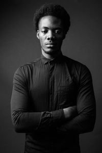 Portrait of young man standing against gray background