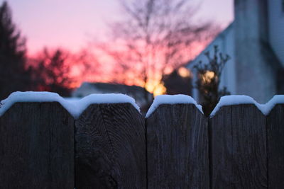 Close-up of snow on wood against sky during sunset