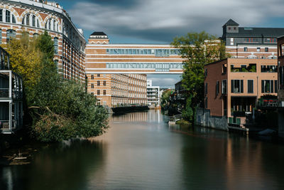 Buildings by river against sky in city