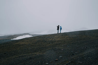 Rear view of people walking on snow covered landscape