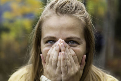 Close-up portrait of woman with hands covering mouth