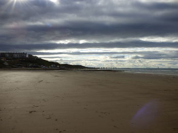 Scenic view of beach against cloudy sky