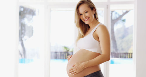 Smiling pregnant woman standing at home