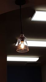 Low angle view of illuminated light bulb hanging from ceiling