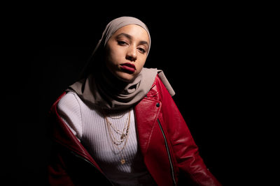 Portrait of beautiful young woman against black background