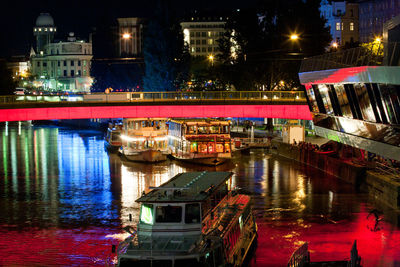 Illuminated bridge over river in city at night