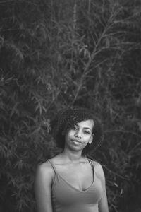 Portrait of smiling young woman standing against plants