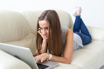 Midsection of woman using mobile phone while sitting on sofa