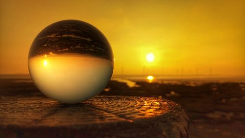 Close-up of crystal ball on water at sunset