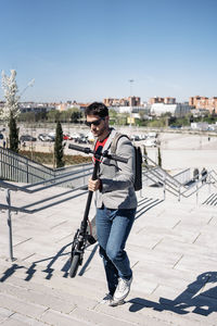 Full length of man standing on railing in city against sky