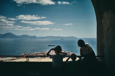 Rear view of people at beach against sky
