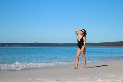 Portrait of young woman in black bikini and brown sunglasses on beach in eastern australia