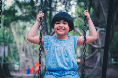 Portrait of smiling girl swinging at playground