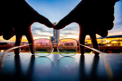 Close-up of hand against sky during sunset