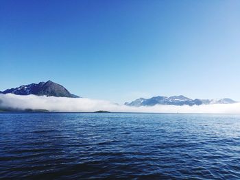 Scenic view of lake and mountains against clear blue sky