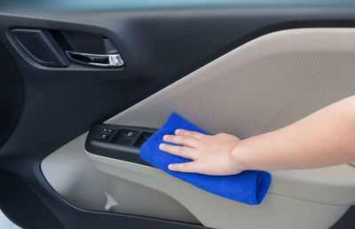 Cropped hand cleaning car door with napkin