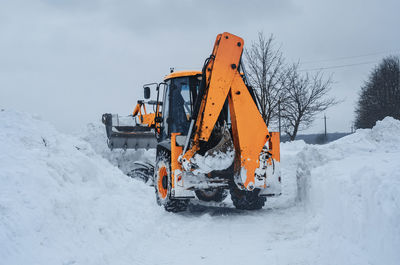 Yellow tractor cleans up snow from road. cleaning and cleaning of roads in city from snow in winter