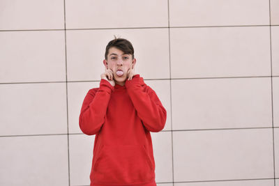 Portrait of young man standing against wall