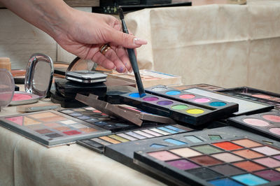 Close-up of woman hand holding make-up brush over palette