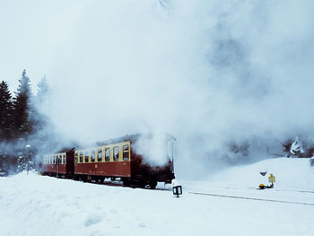 Train on snow covered landscape against sky