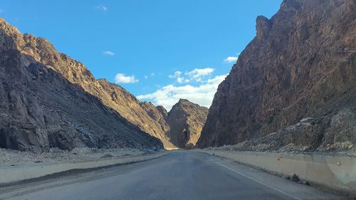 Road amidst mountains against clear blue sky