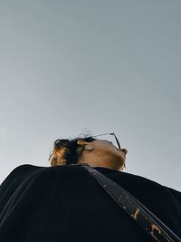 Low angle view of young woman looking away against clear sky