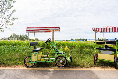 Bicycle parked on field by road against sky