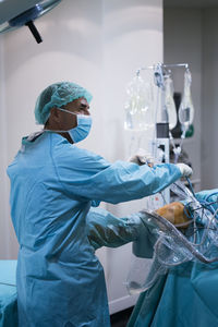 Side view of man in surgeon uniform looking away while conducting surgery on leg of† patient